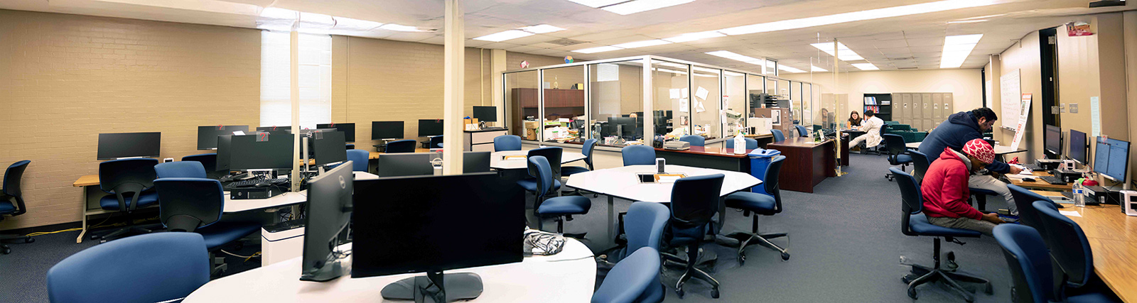 Interior view of the math lab, with many tables and computers, and a few people studying