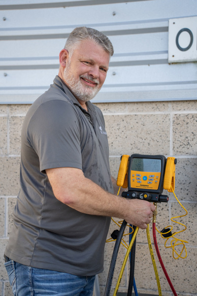 Chris Avirett smiles and operates HVAC machinery outdoors