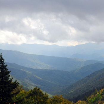 View of a valley between the Smoky Mountains with misty clouds overhead